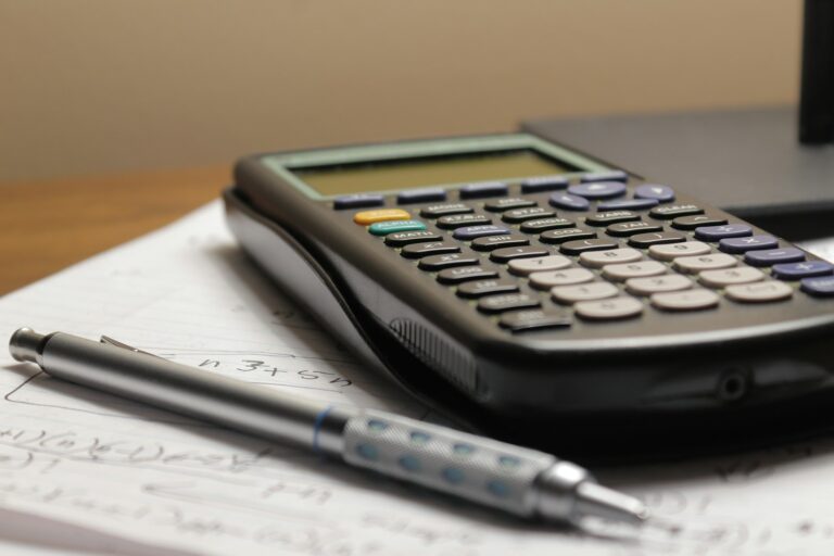 Calculadora, documentos y bolígrafo para revisar gastos de pensión alimenticia